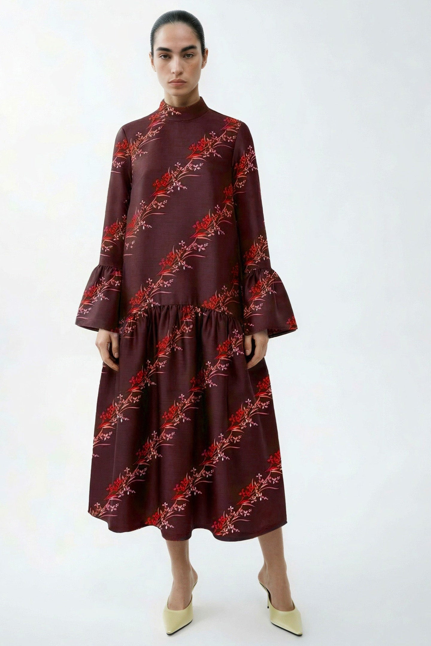 Woman wearing a burgundy dress with floral pattern on a white background